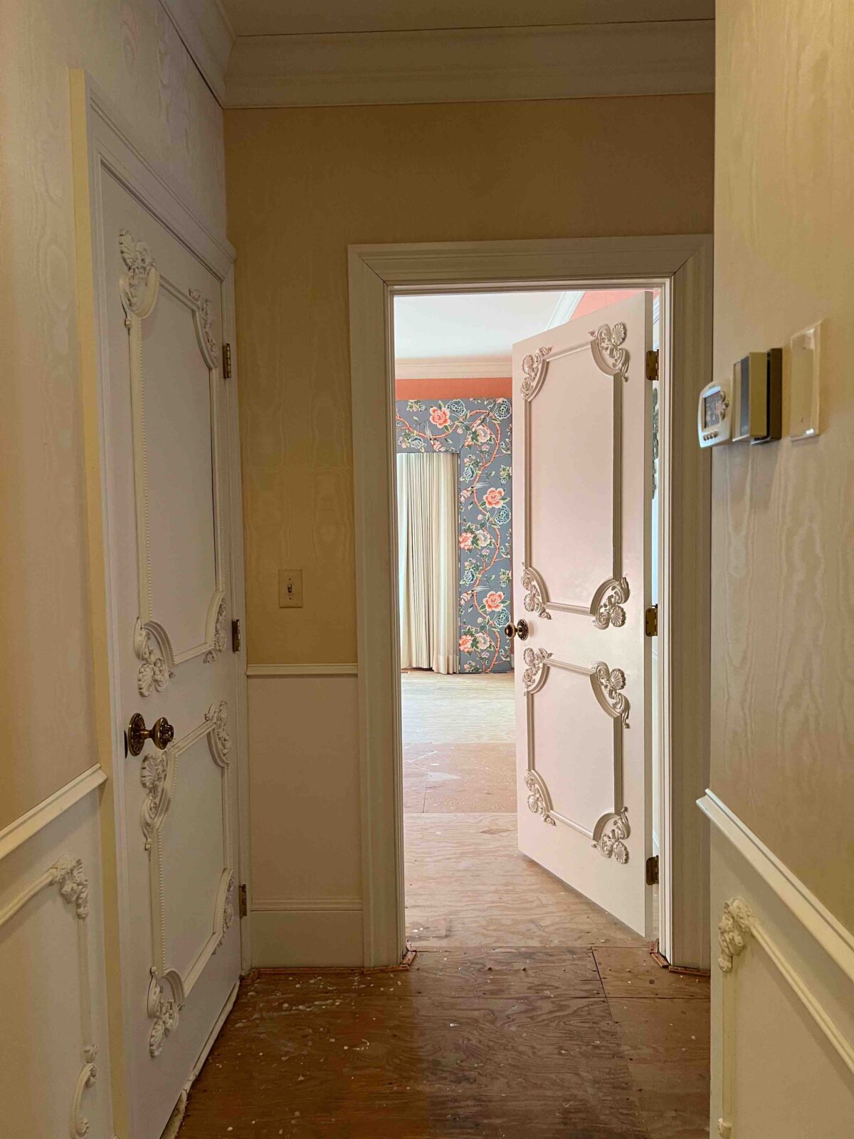 Hallway with wallpaper, wainscoting, and ornate details on the woodwork