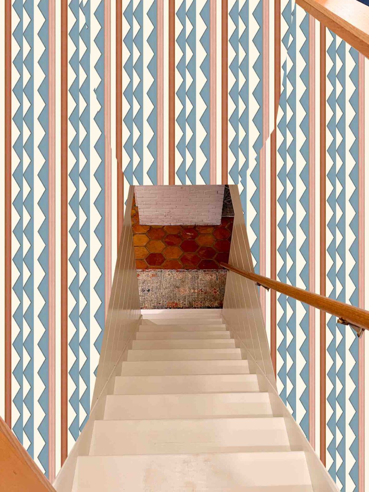 White-painted basement stairwell with a mock-up of an Ottoline wallpaper installed at the top