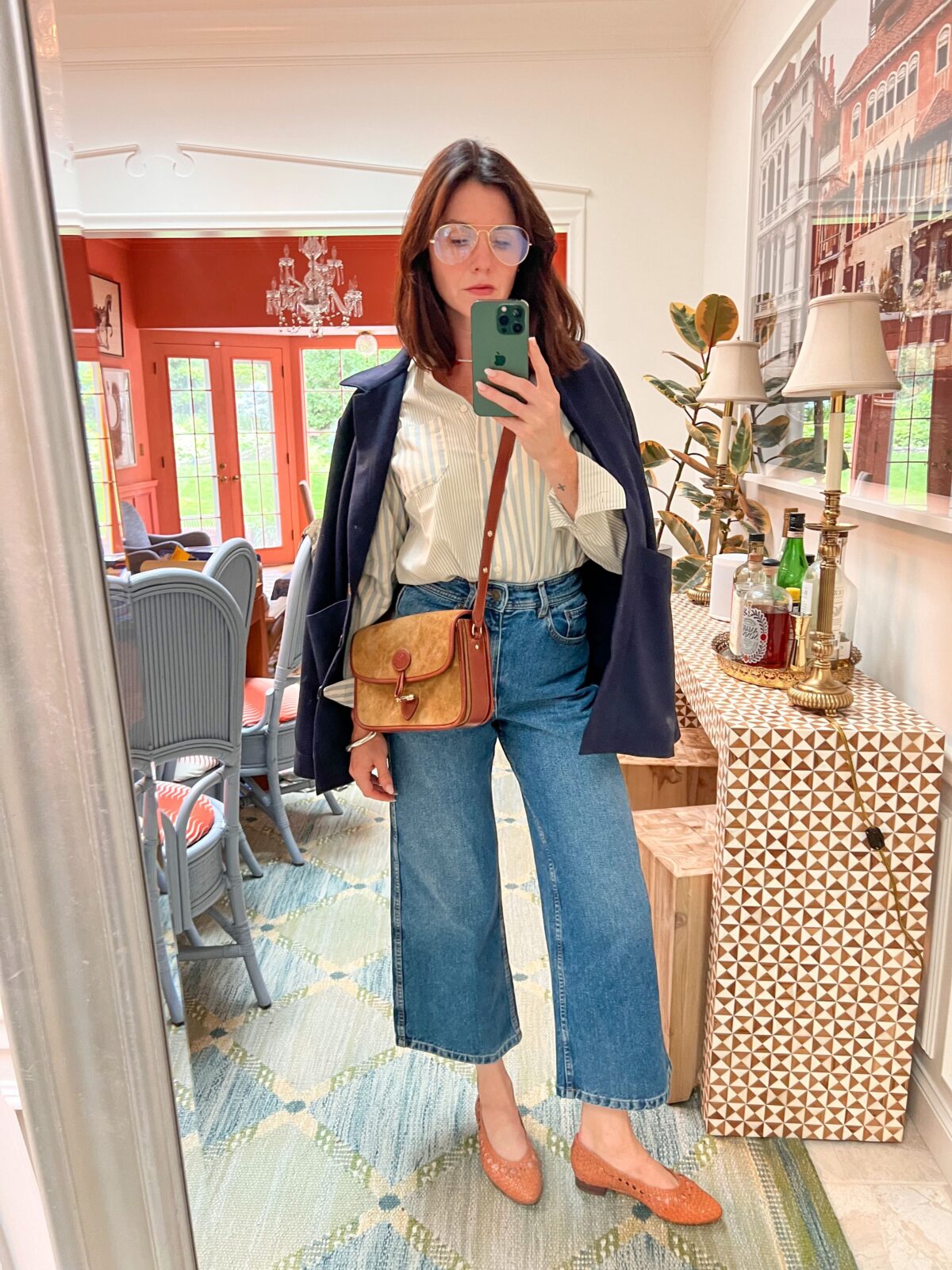 Woman standing in front of a mirror taking a selfie. She's wearing some fall wardrobe staples: wide-leg denim, button-down shirt, blazer. 