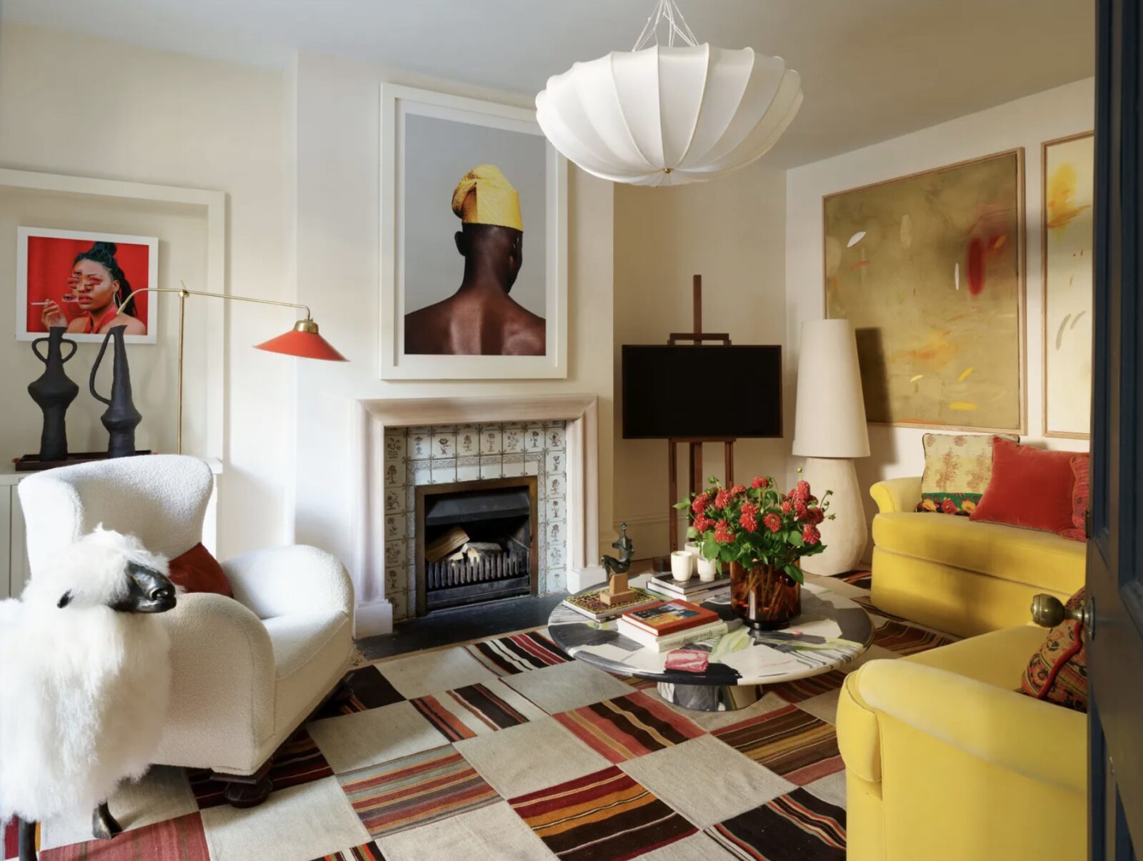 Living room with striped/checkered rug, white armchair, yellow velvet sofa, and large-scale colorful pieces of art