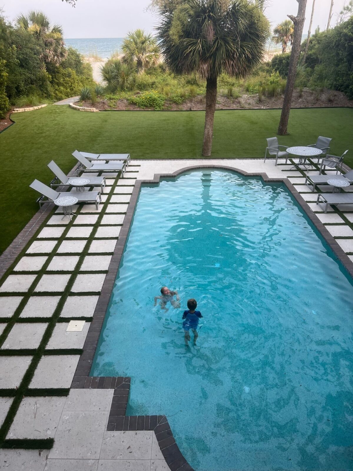 Swimming in a backyard pool in Hilton Head with a path to the ocean shown in the background
