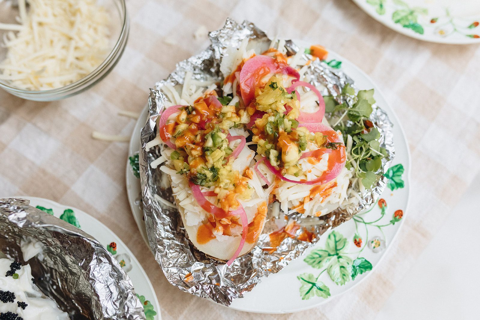 A baked potato topped with Mango Habenero Cheddar Gruyere with Mango Salsa and pickled onions